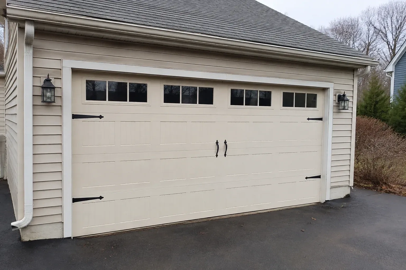 Cream carriage-house-style garage door with dark decorative hardware. — Carriage-House Garage Door Installation, Kitchener